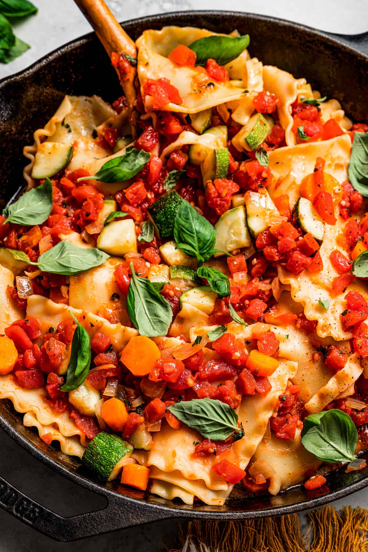 Close-up of lasagna noodles topped with tomatoes and basil leaves.