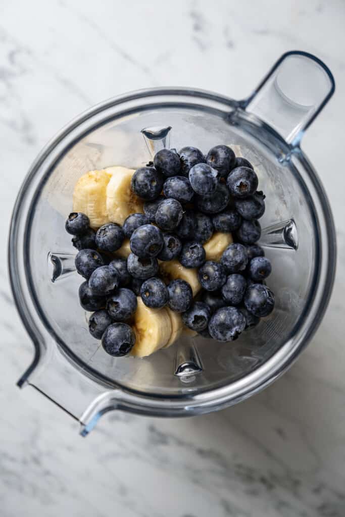 Sliced bananas and blueberries in a food processor.