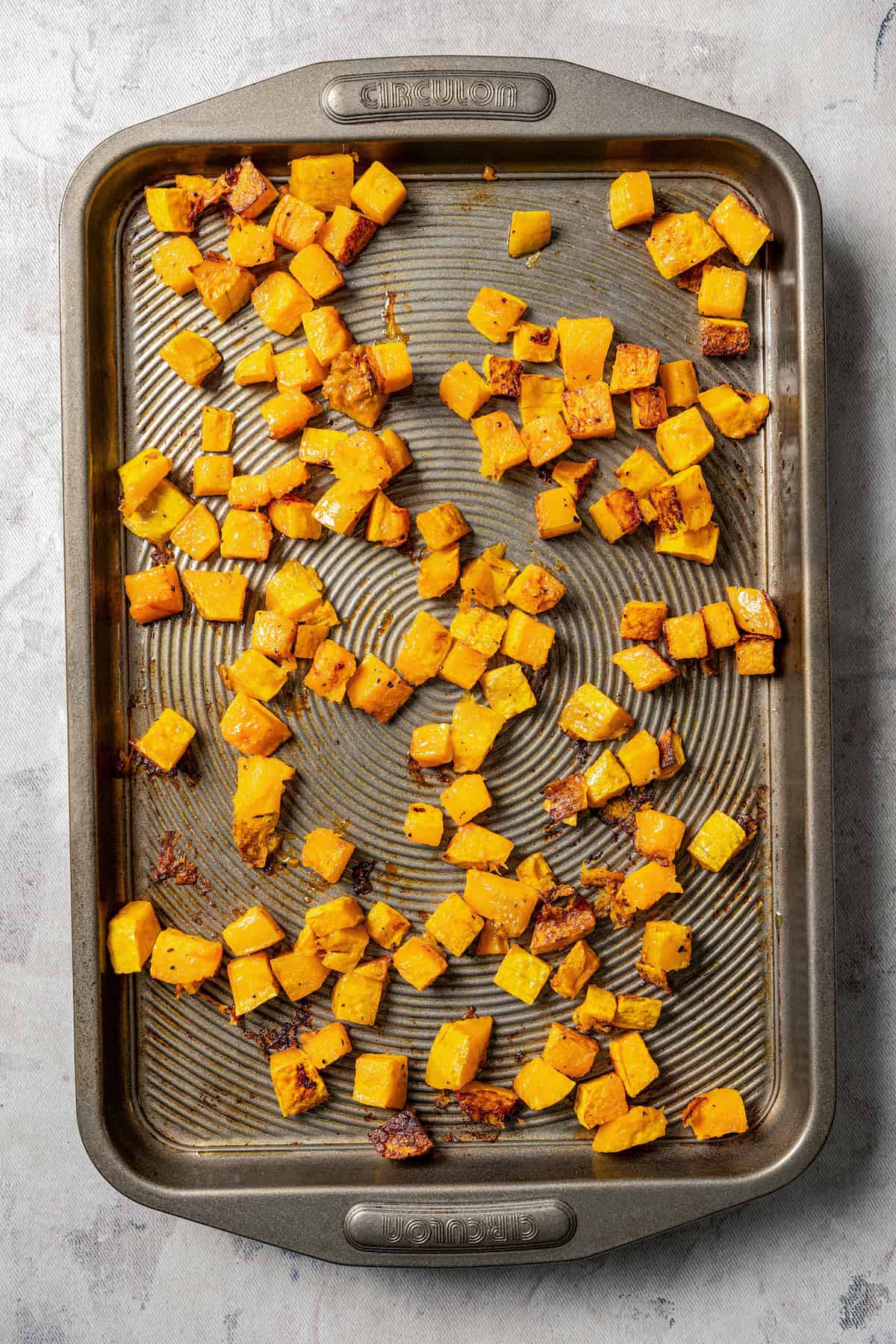 Roasted butternut squash cubes on a baking sheet.