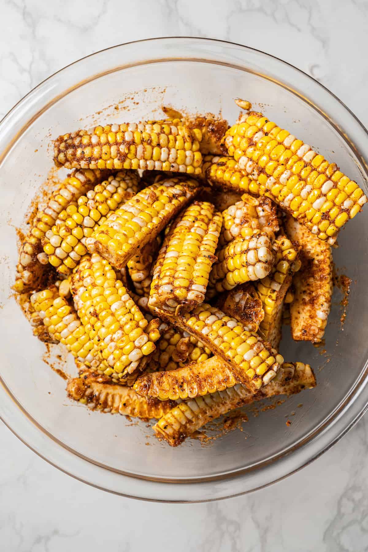 Seasoned corn ribs in a glass bowl.