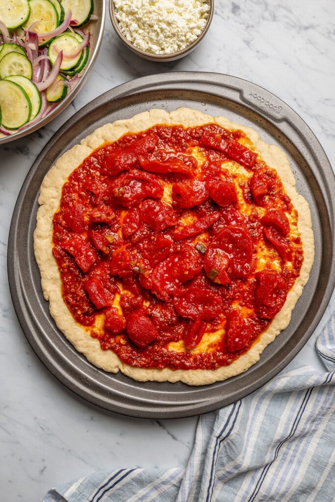 Pizza crust topped with pizza sauce and stewed diced tomatoes.