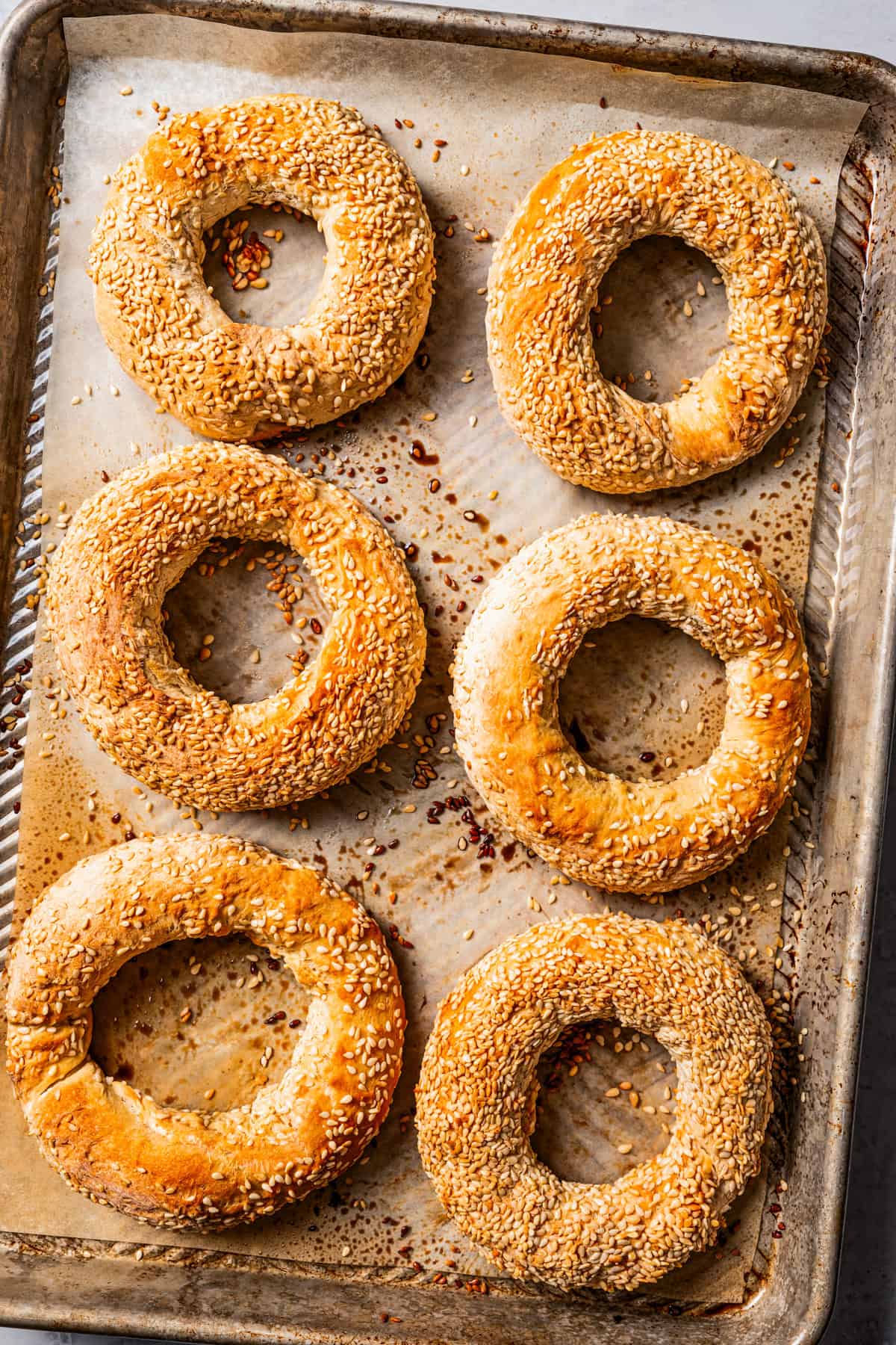 Baked sesame bagels (gevrek) on a lined baking sheet.