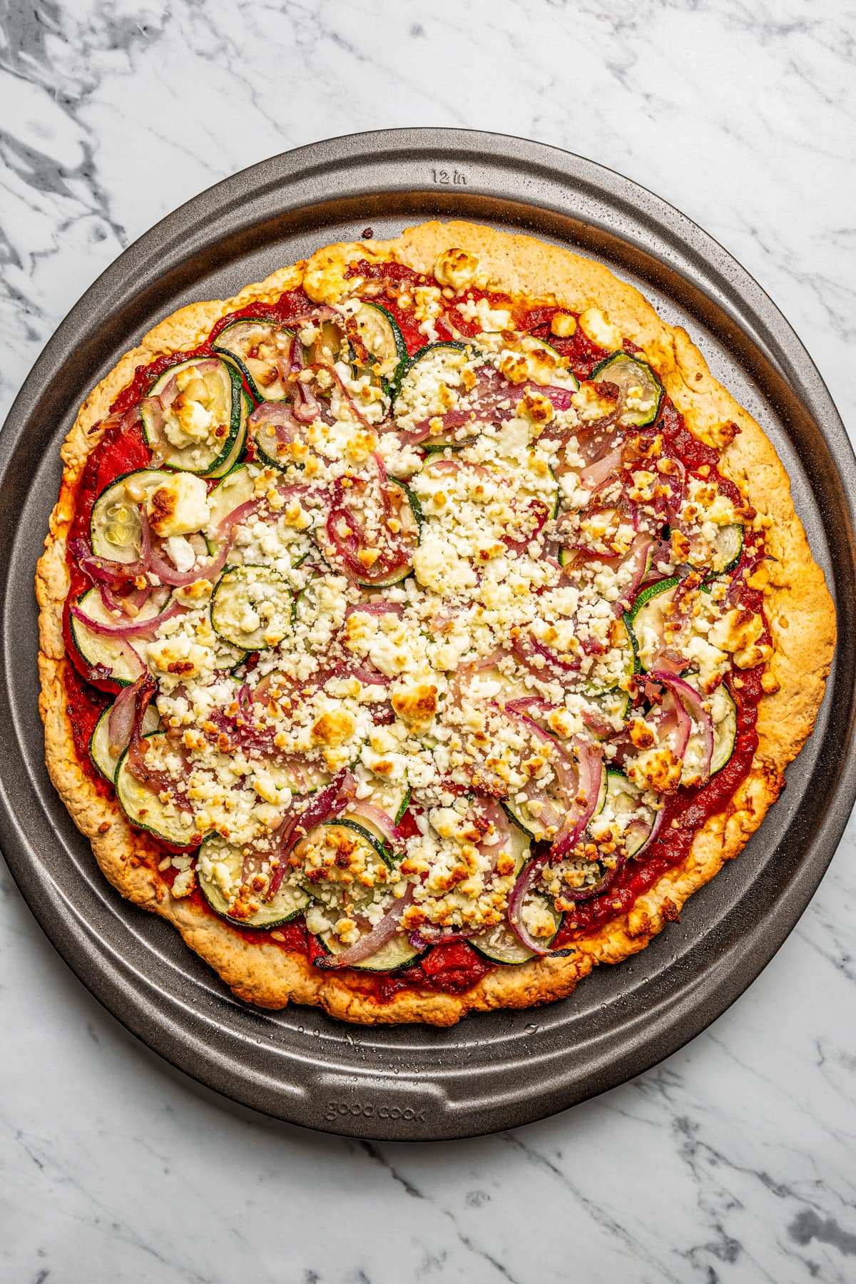 Baked zucchini goat cheese pizza placed on a baking sheet.