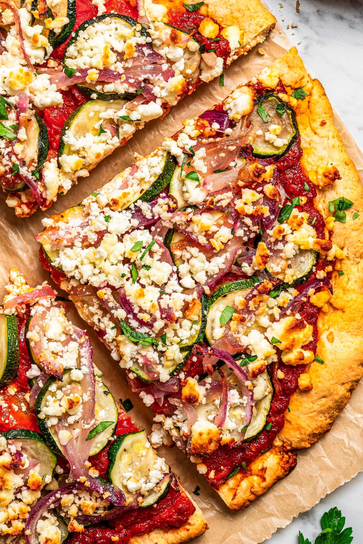 Close-up image of a pizza slice topped with goat cheese and zucchini.