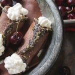 Chocolate cannoli shells are filled with whipped cream in a dark bowl