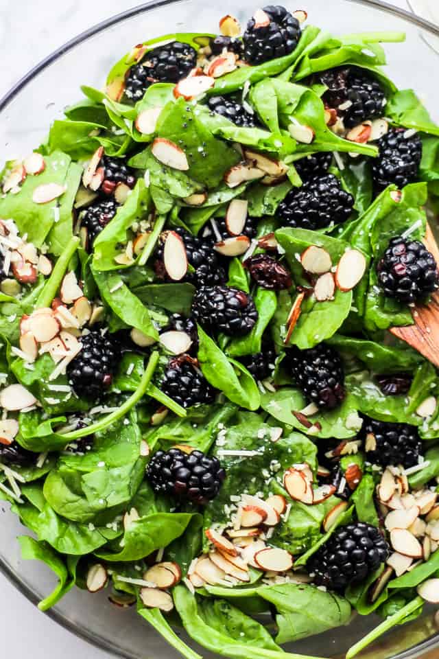 Spinach Salad with blackberries served in a clear glass salad bowl