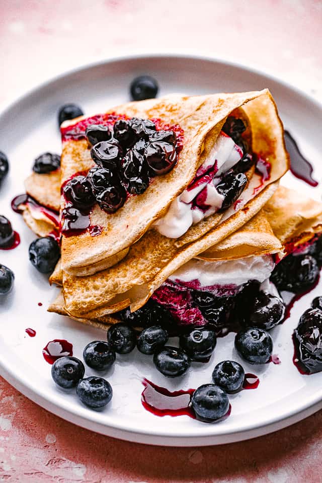 stacked folded crepes with blueberry sauce