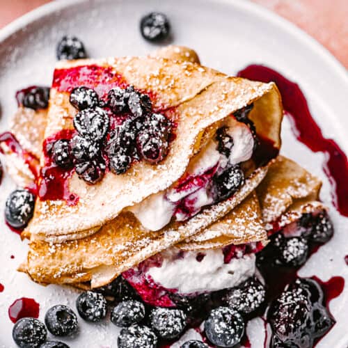 crepes filled with whipped cream and topped with blueberry sauce.