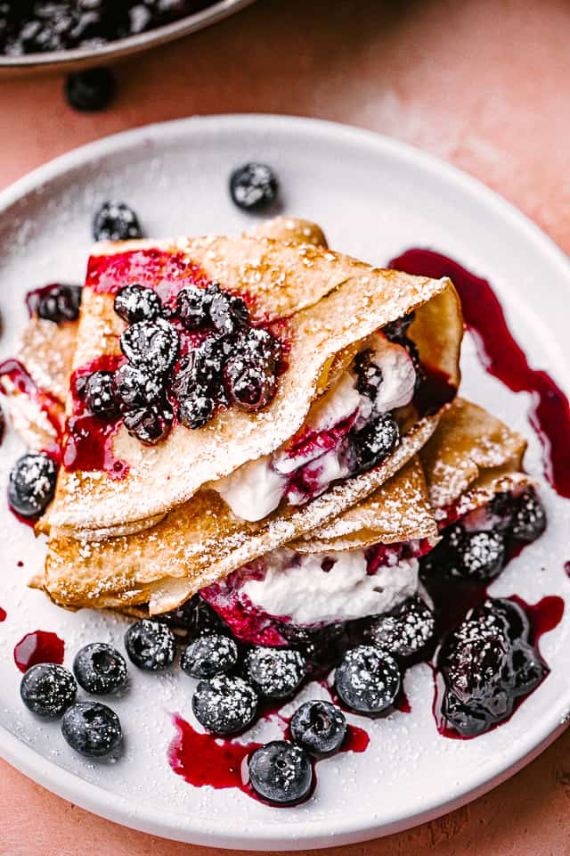 crepes filled with whipped cream and topped with blueberry sauce.