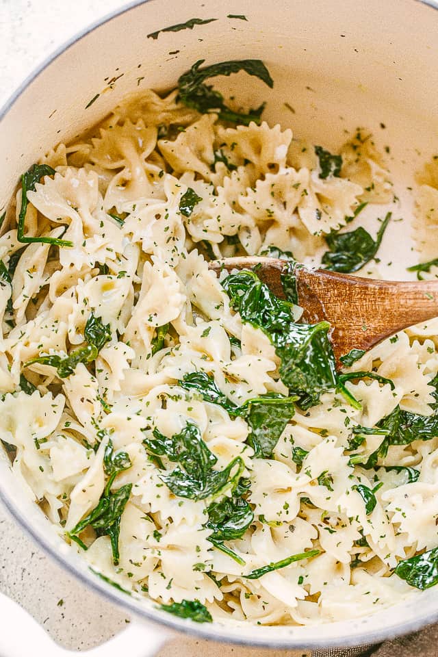 Dutch oven with bow tie pasta and spinach.