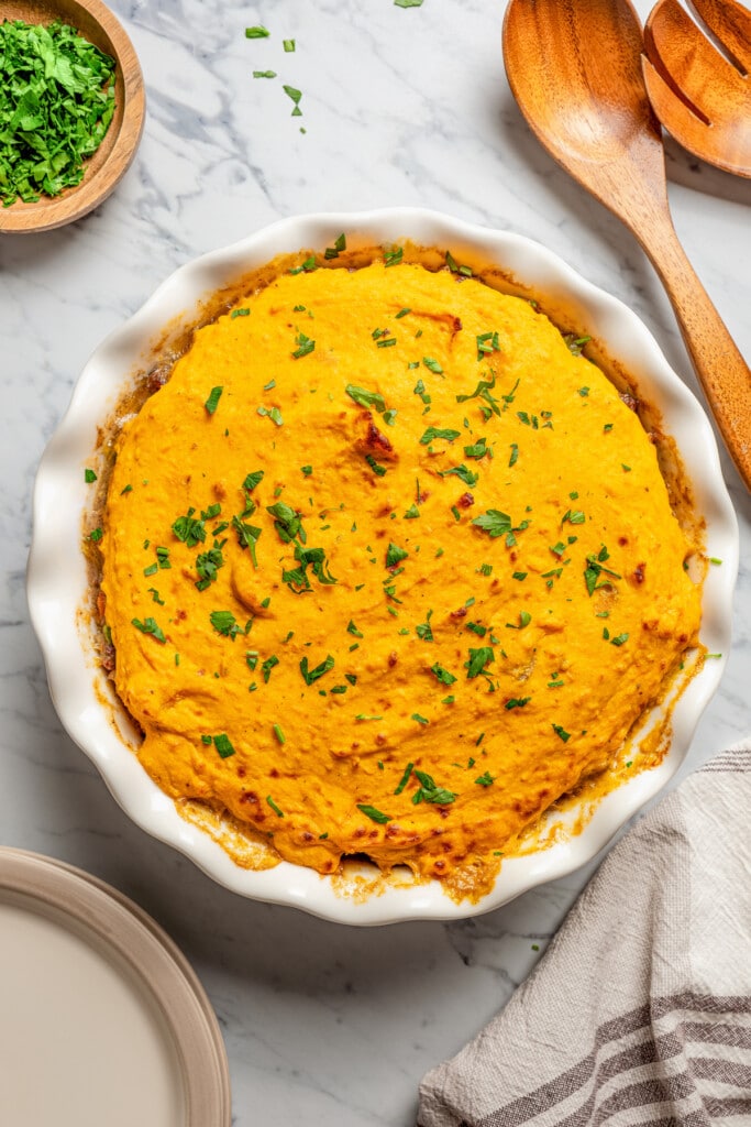 Baked sweet potato shepherd's pie garnished with parsley in a pie plate.