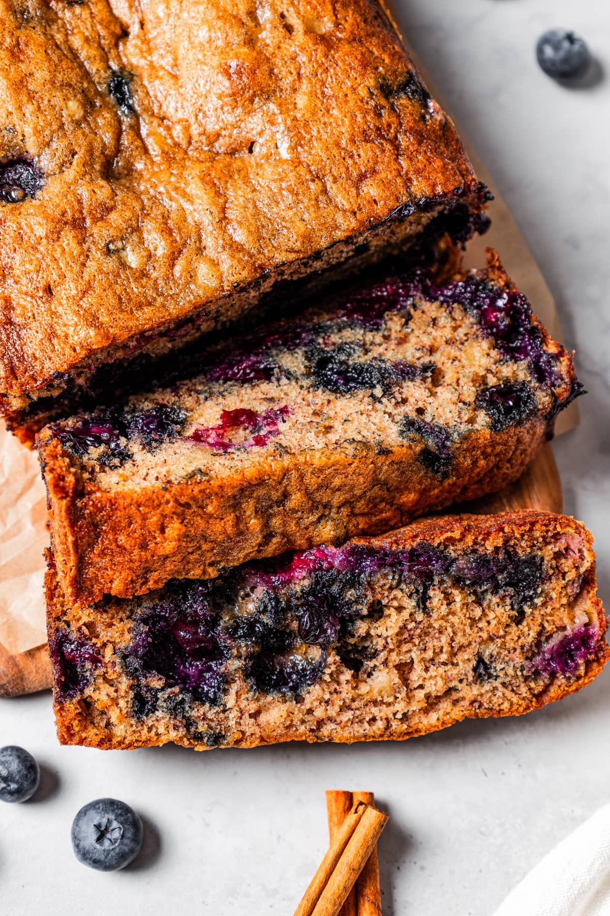 Close-up overhead view of a loaf of blueberry banana bread cut into slices.