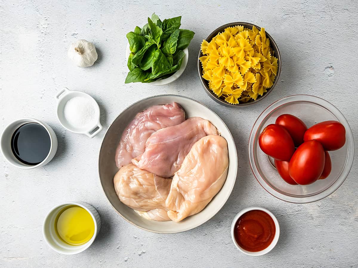 This easy bruschetta chicken pasta is loaded with juicy chicken, fresh tomatoes, and basil, all tossed in a garlicky homemade balsamic dressing. Ingredients for Bruschetta chicken Pasta laid out in bowls on the counter.
