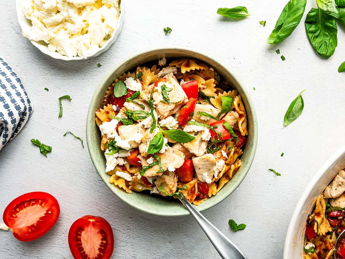 This easy bruschetta chicken pasta is loaded with juicy chicken, fresh tomatoes, and basil, all tossed in a garlicky homemade balsamic dressing. A bowl with a single serving of Chicken Pasta.