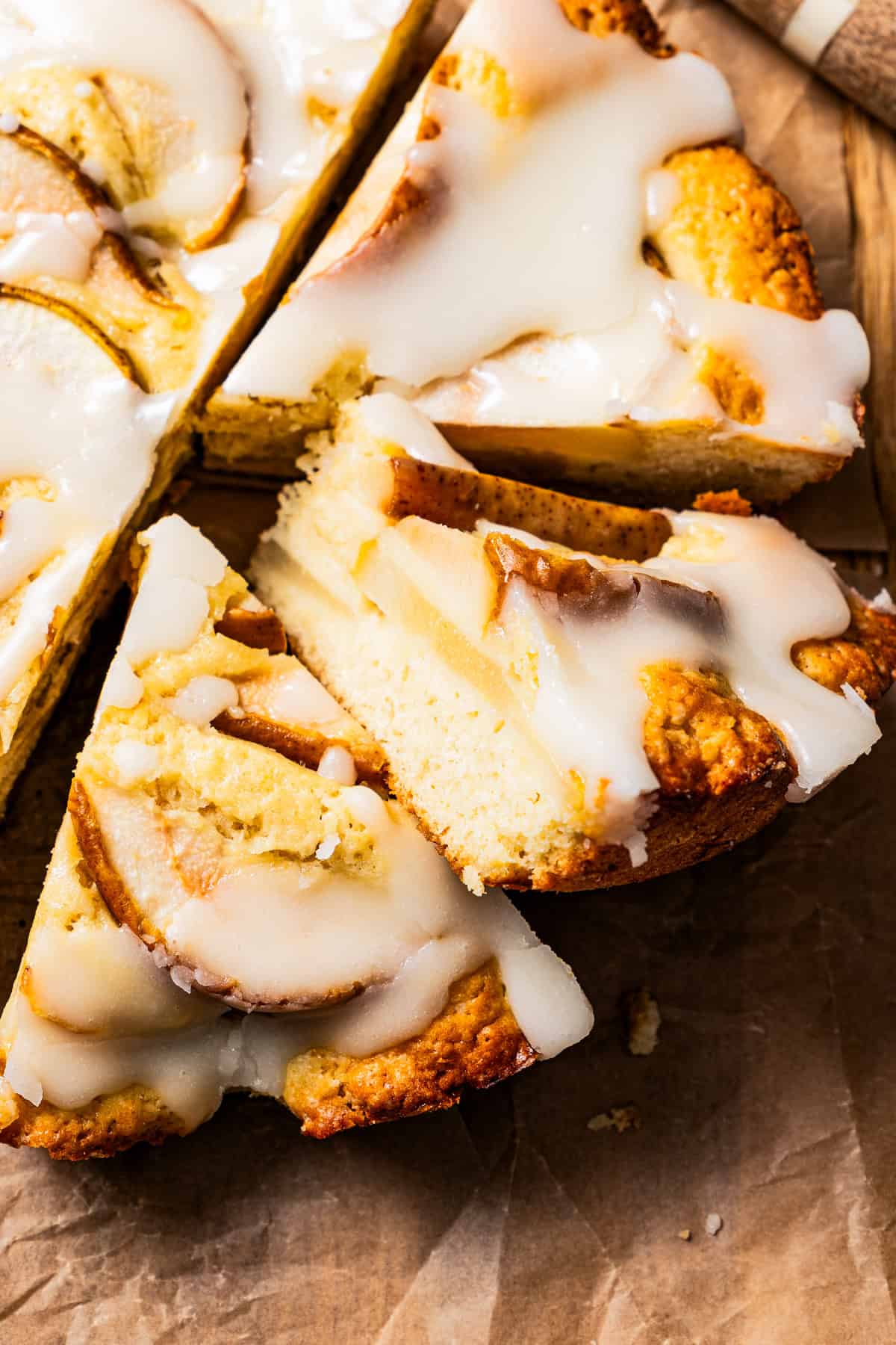 Sliced pear cake arranged on a brown parchment paper.