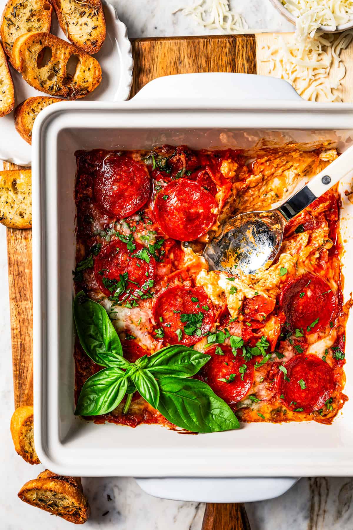 Overhead view of pizza dip in a baking dish with a spoon for serving.