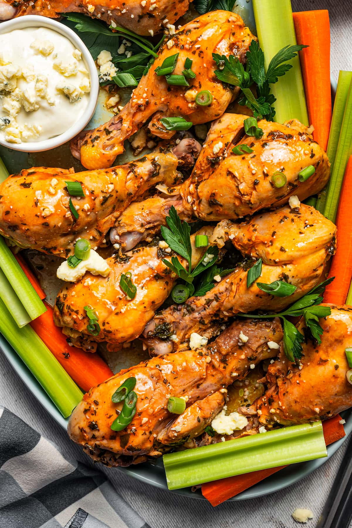 Buffalo chicken drumsticks, carrot sticks, and celery arranged on a platter with blue cheese dip.