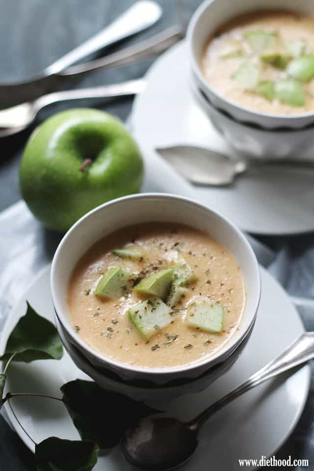 Cheddar Cheese Soup in a white bowl with apples pieces on top