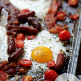 Eggs, bacon, sausage, and tomatoes on a baking sheet.