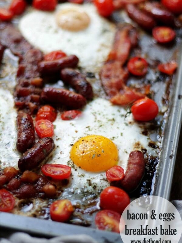Eggs, bacon, sausage, and tomatoes on a baking sheet.