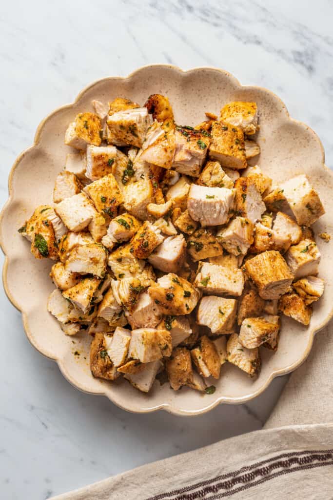 A plate full of cubed, cooked chicken breasts