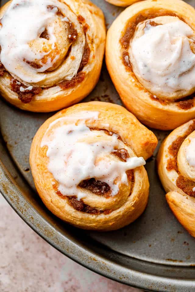 Overhead shot of pumpkin pie cinnamon rolls iced with cream cheese frosting.