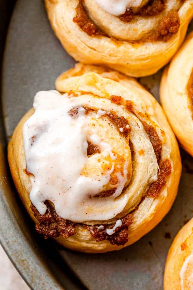 Close-up image of pumpkin pie cinnamon rolls iced with cream cheese frosting.