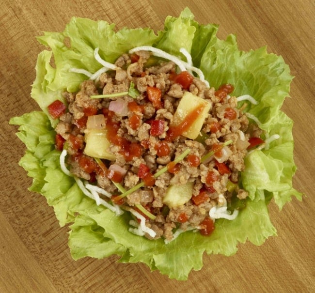 Top view of a lettuce bowl filled with ground pork and pineapple mixture and drizzled with sriracha sauce