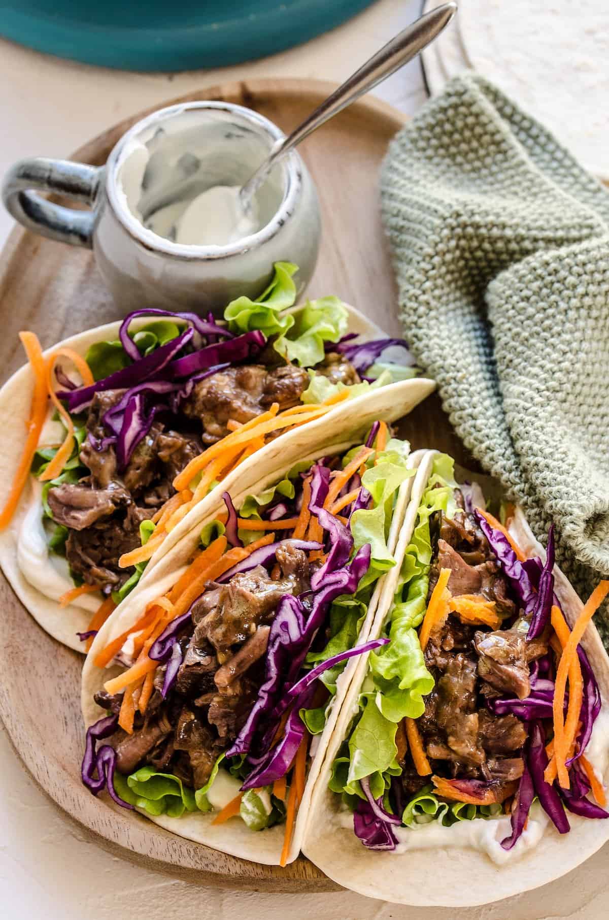 Three Korean beef tacos filled with shredded BBQ beef and veggies.