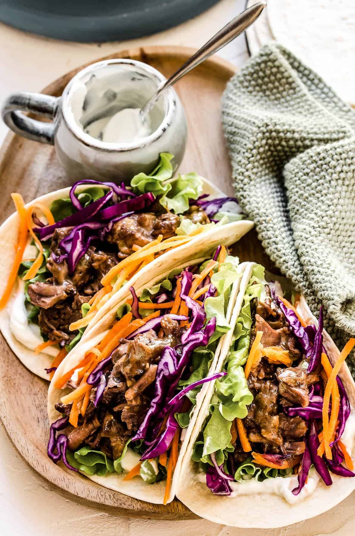 Three Korean beef tacos filled with shredded BBQ beef and veggies.