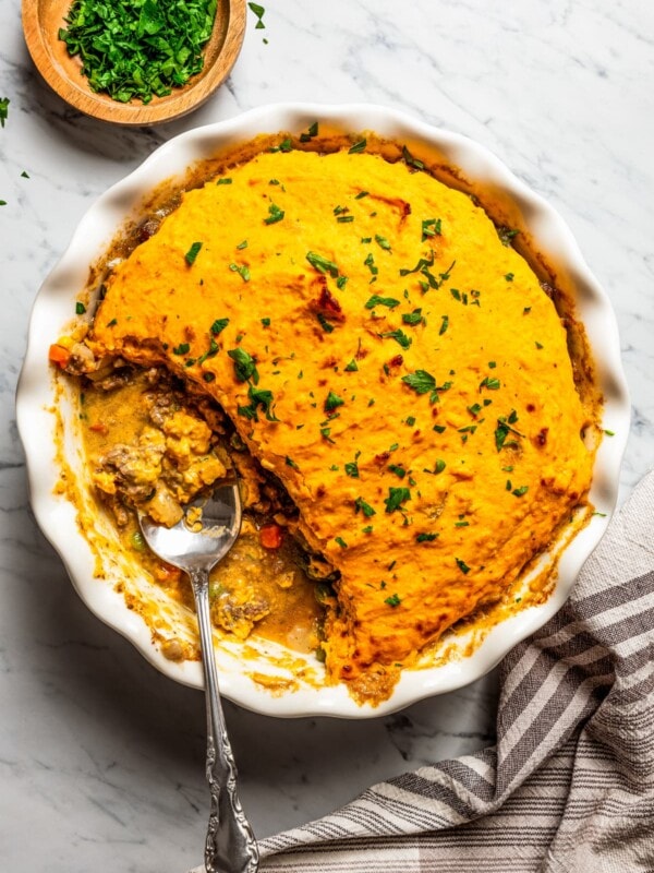 Overhead shot of a pie dish with a sweet potato shepherd's pie and a spoon resting inside of the baking dish.
