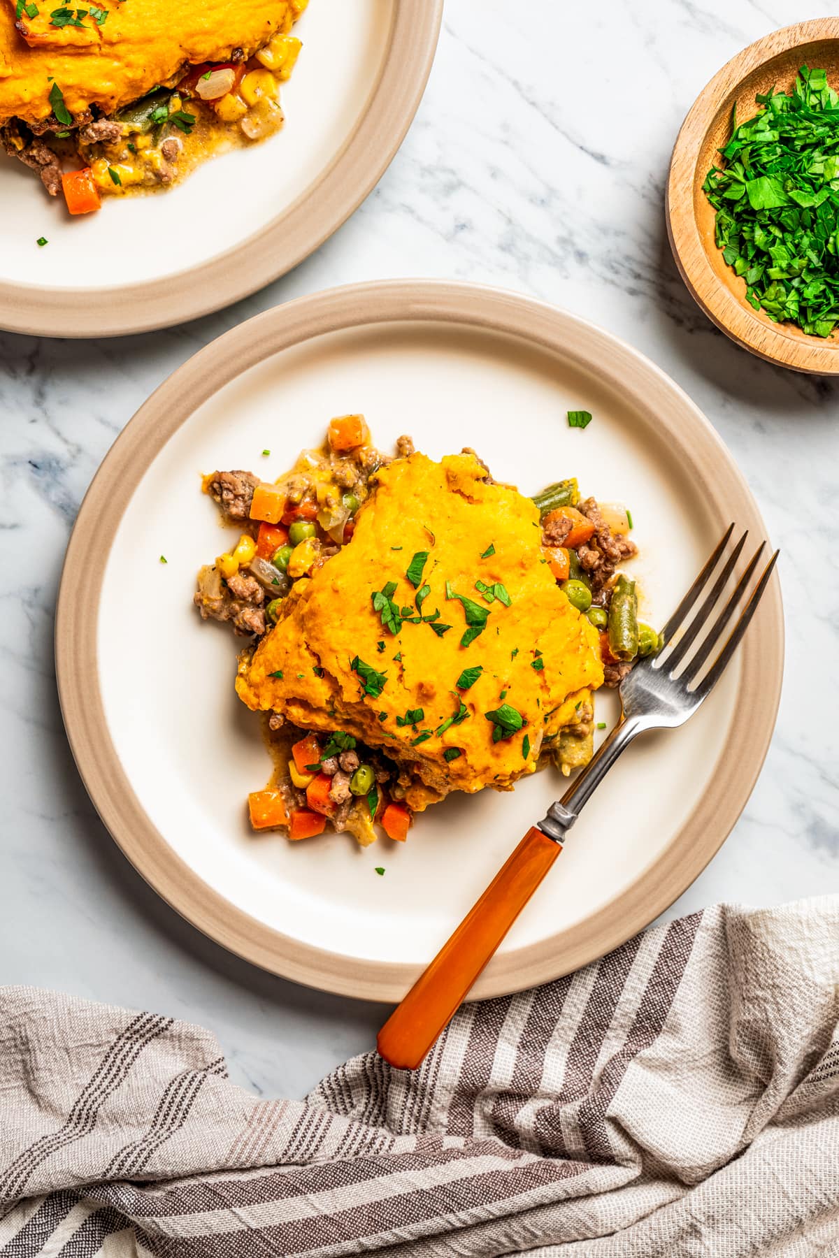 Image of a serving of sweet potato shepherd's pie on a white dinner plate next to a fork.