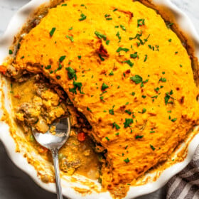 Overhead view of a baking dish with a sweet potato shepherd's pie and a spoon resting inside of the baking dish.