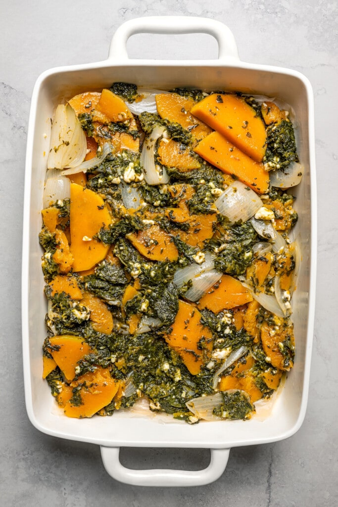 Butternut squash and spinach pie filling layered over phyllo sheets in a baking dish.
