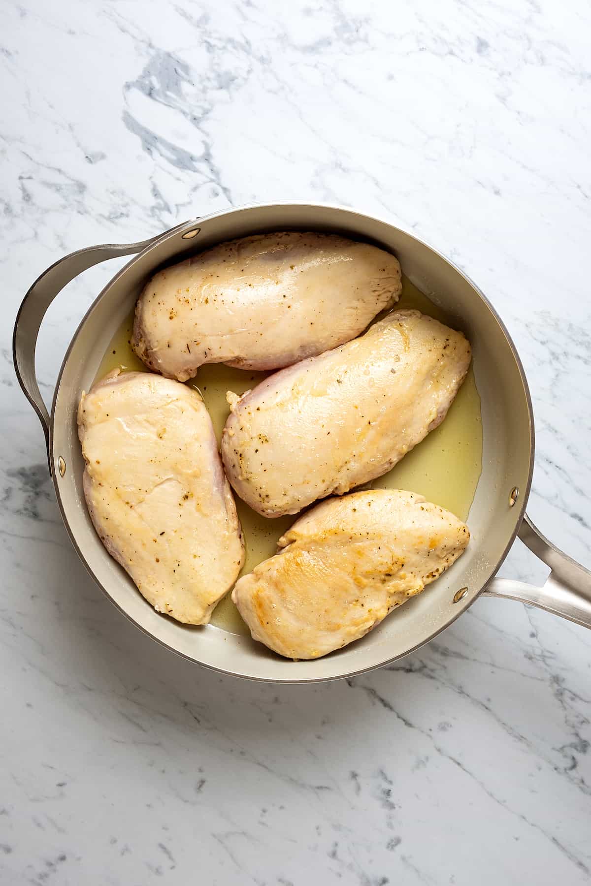 Browned coated chicken breasts in a large skillet.