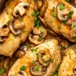 Close up top view of chicken marsala in a large skillet, topped with mushrooms and marsala wine sauce.