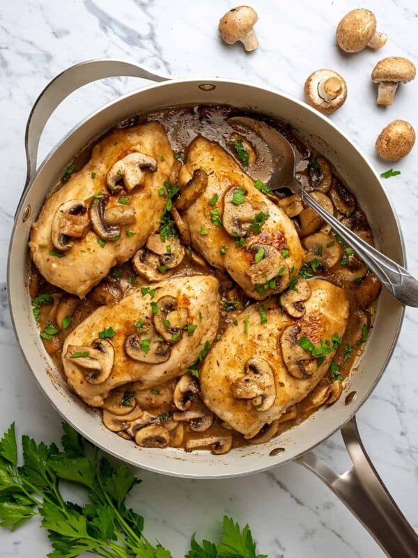 Top view of chicken marsala in a large skillet, topped with mushrooms and marsala wine sauce.