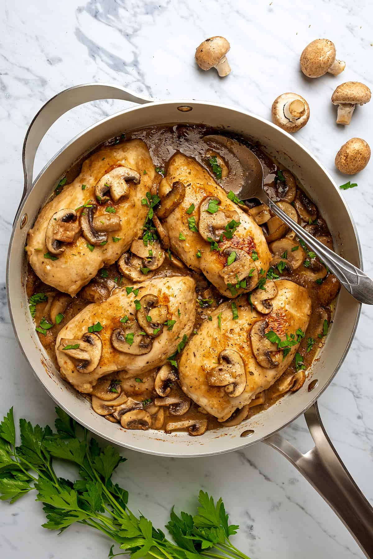 Top view of chicken marsala in a large skillet, topped with mushrooms and marsala wine sauce.