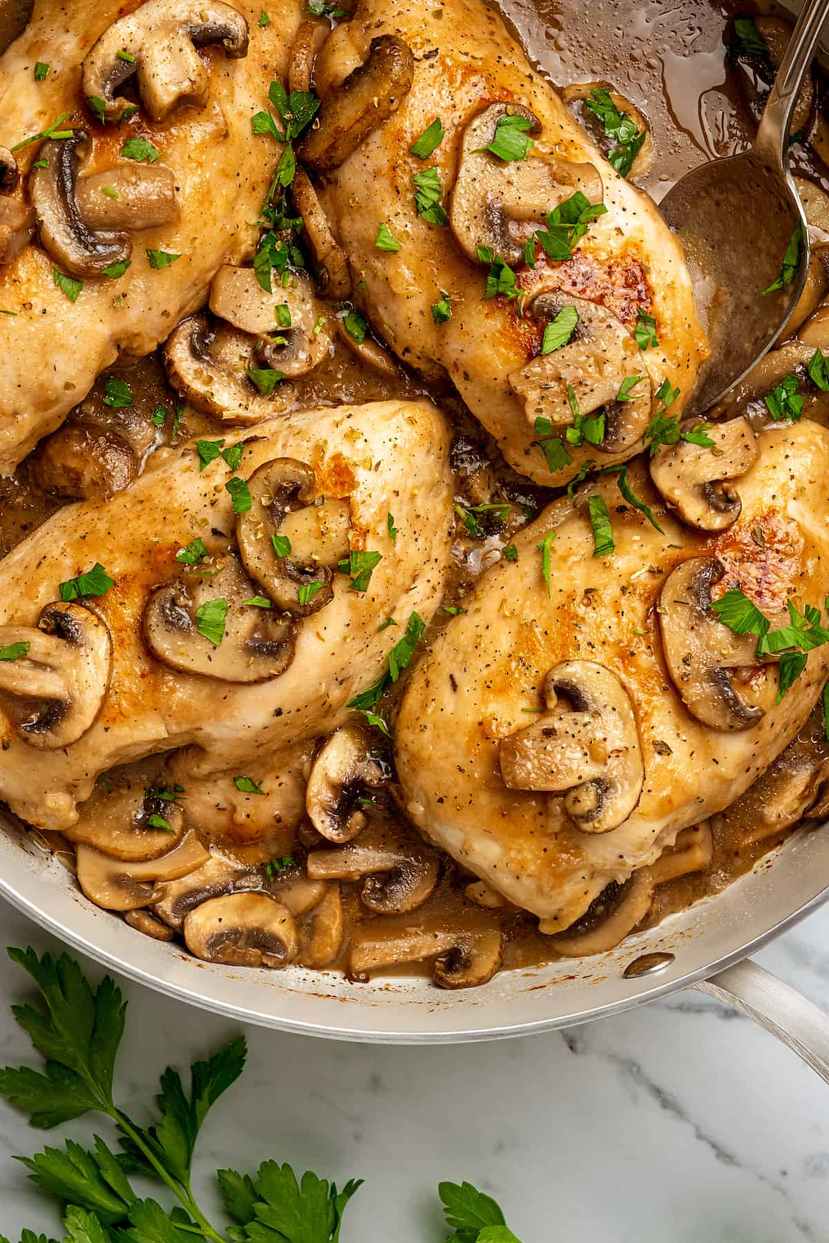 Top view of chicken marsala in a large skillet, topped with mushrooms and marsala wine sauce.