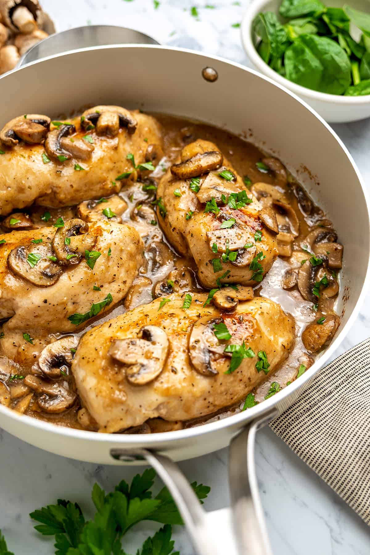 Chicken marsala in a large skillet, topped with mushrooms and marsala wine sauce.