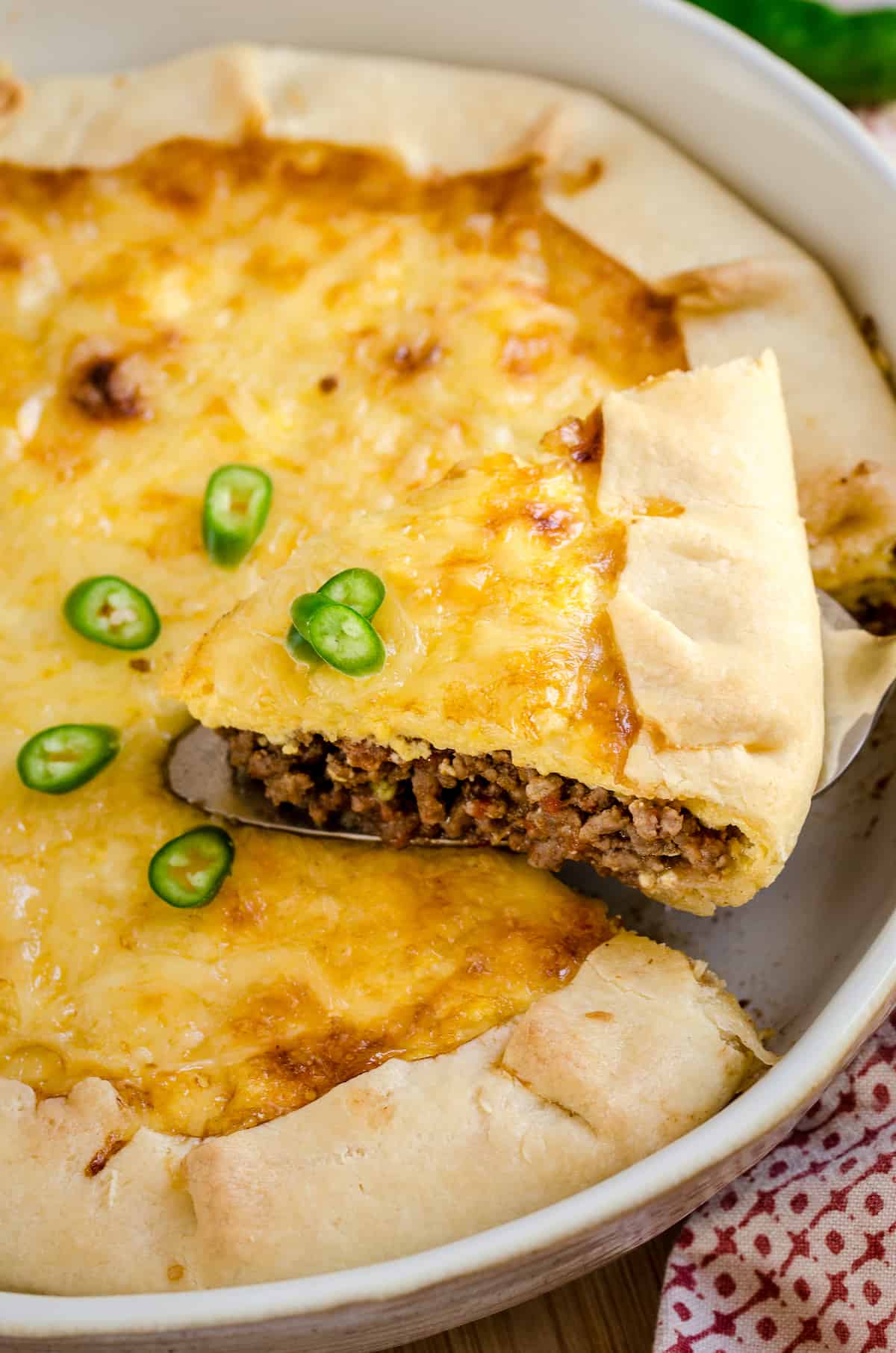 A slice of Tex-Mex cheesy quiche is served from a baking dish.