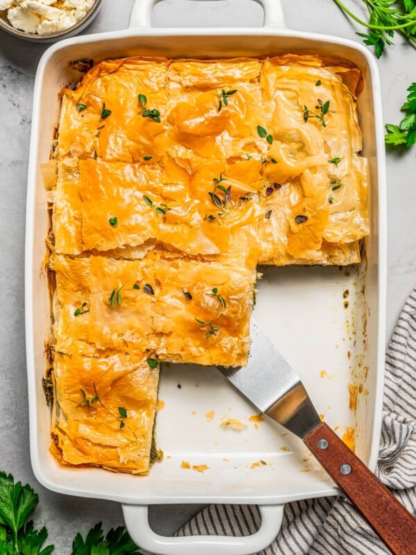 Overhead view of butternut squash and spinach pie in a baking dish, with sliced missing.