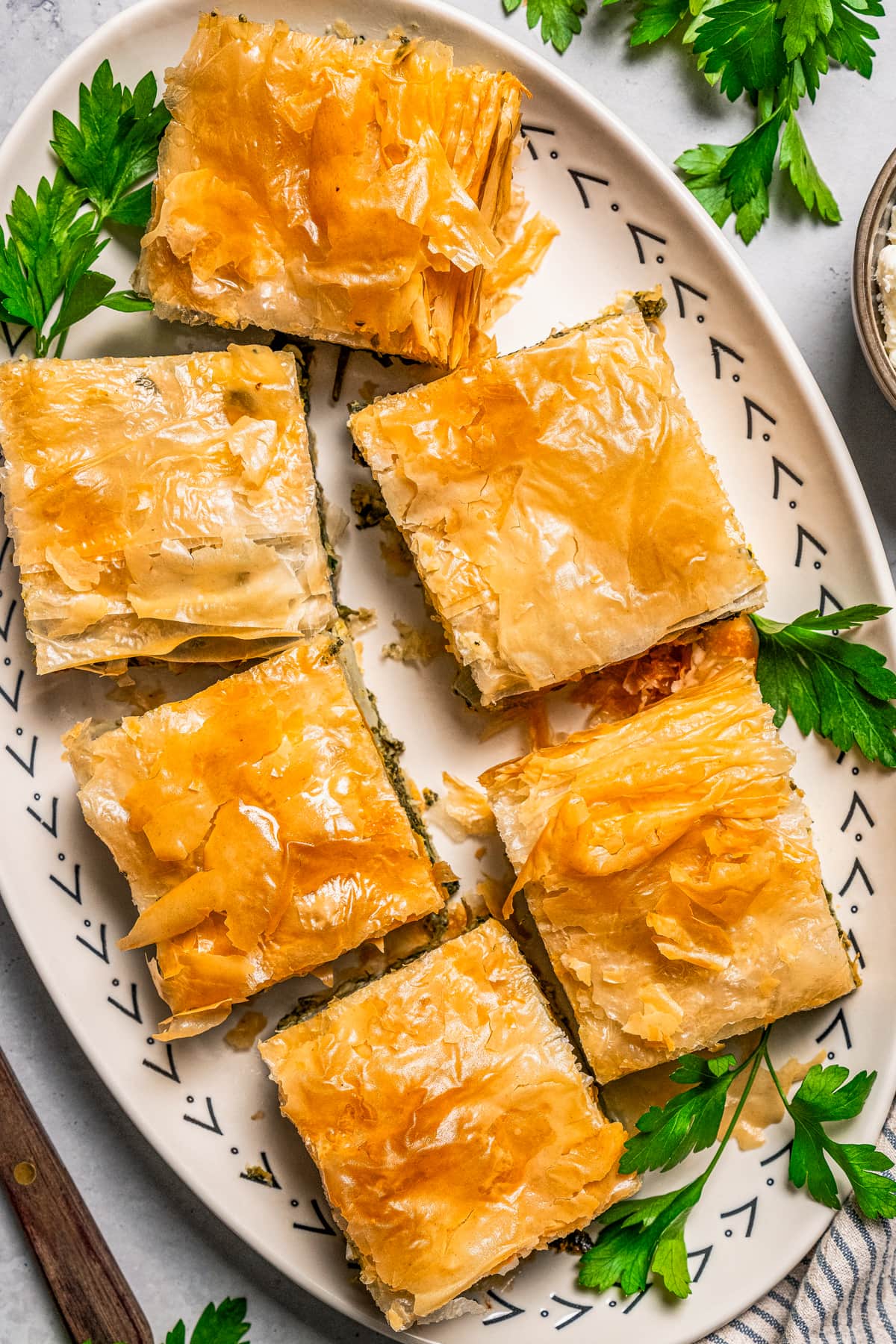 Overhead view of slices of butternut squash and spinach pie arranged on a platter.