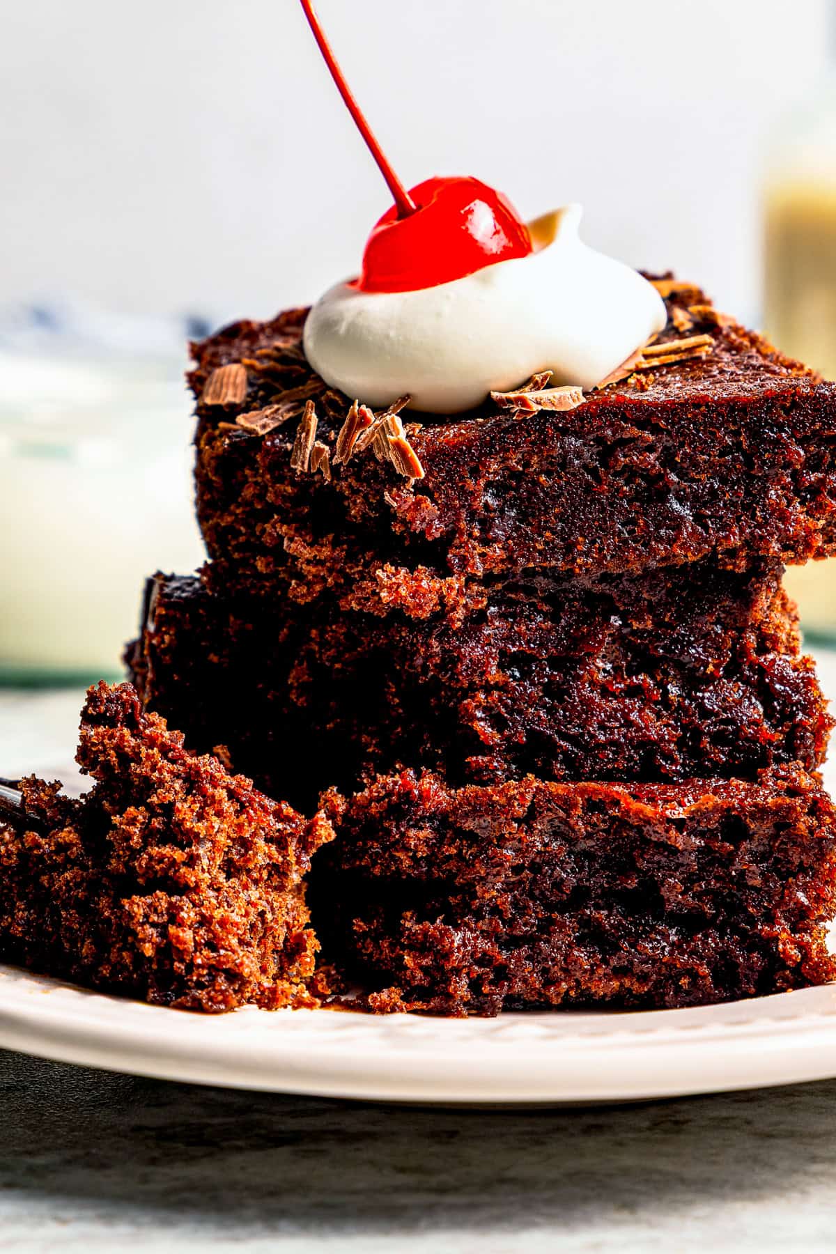 These delicious, moist, fudgy 2-ingredient brownies are made with only a boxed brownie mix and Sprite. That's it! The easiest dessert ever. A stack of three 2-ingredient brownies topped with a dollop of whipped cream and a maraschino cherry.