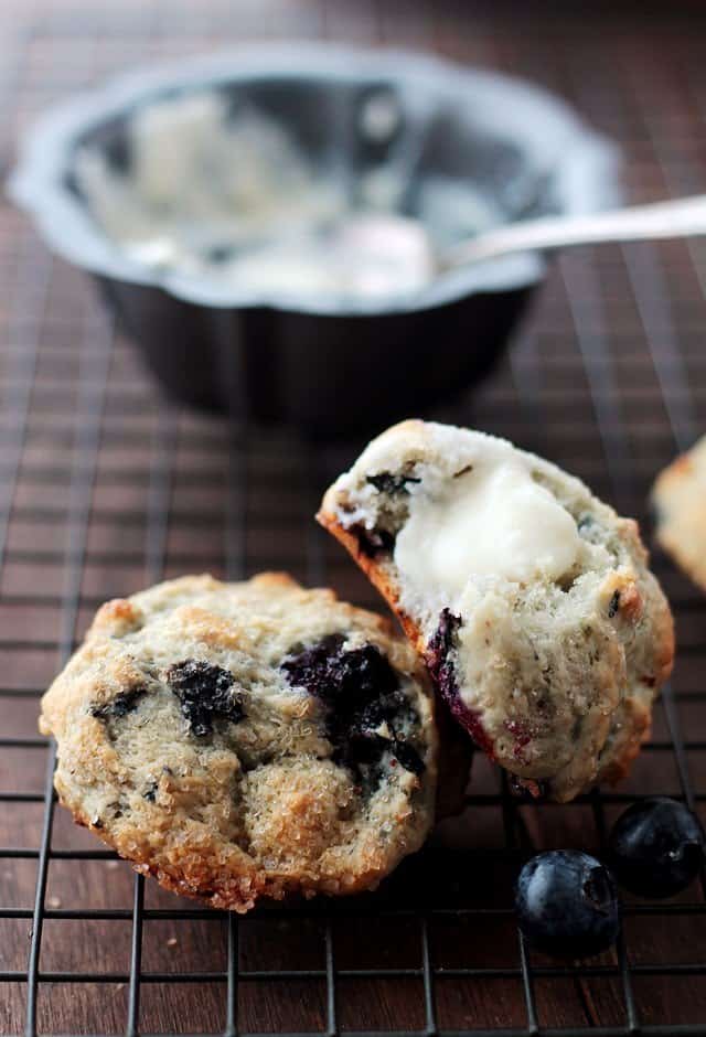 Two Blueberry Scones on a wire rack and a dollop of Cream Cheese Frosting on one scone