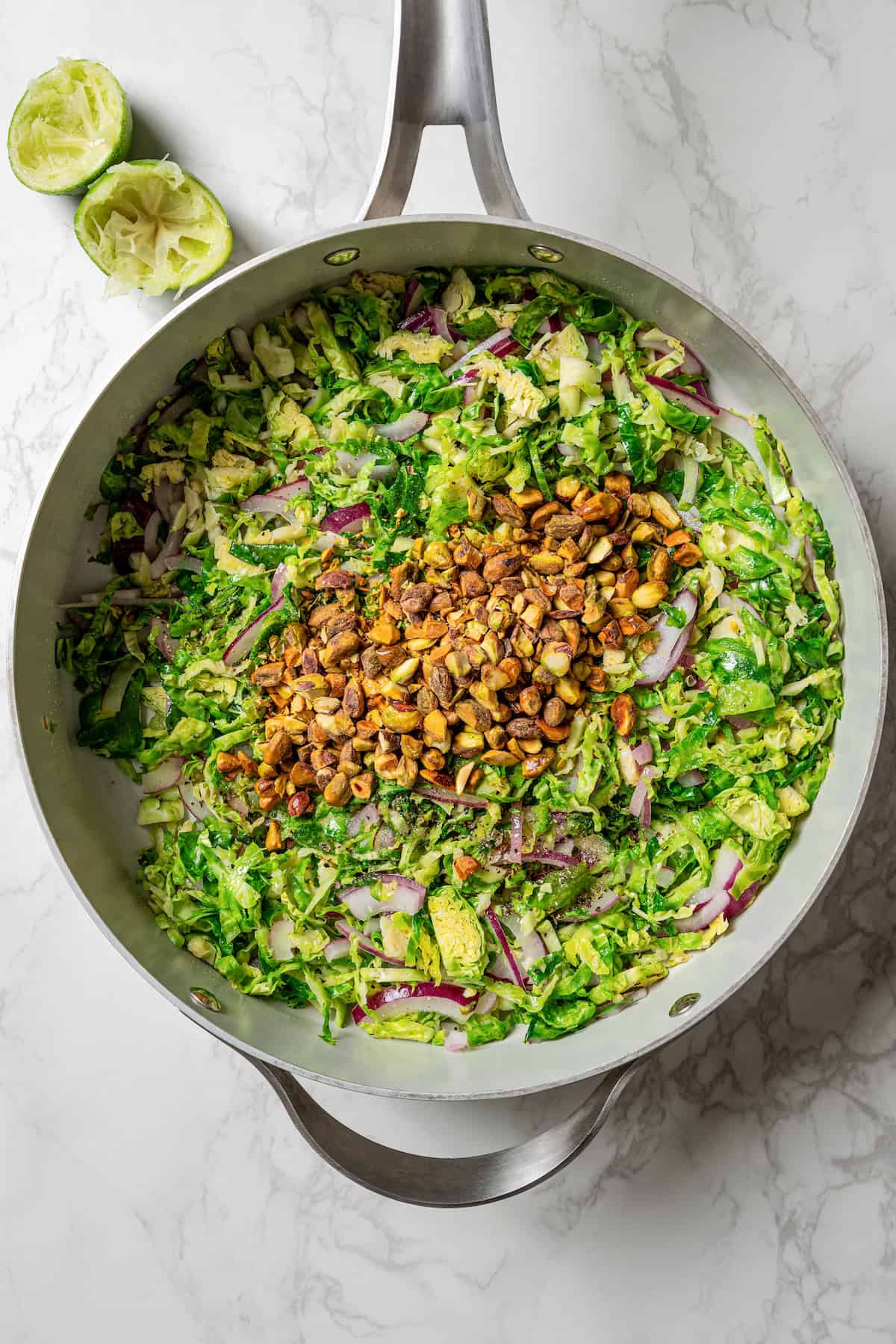 Shaved Brussels sprouts salad ingredients combined in a large skillet.