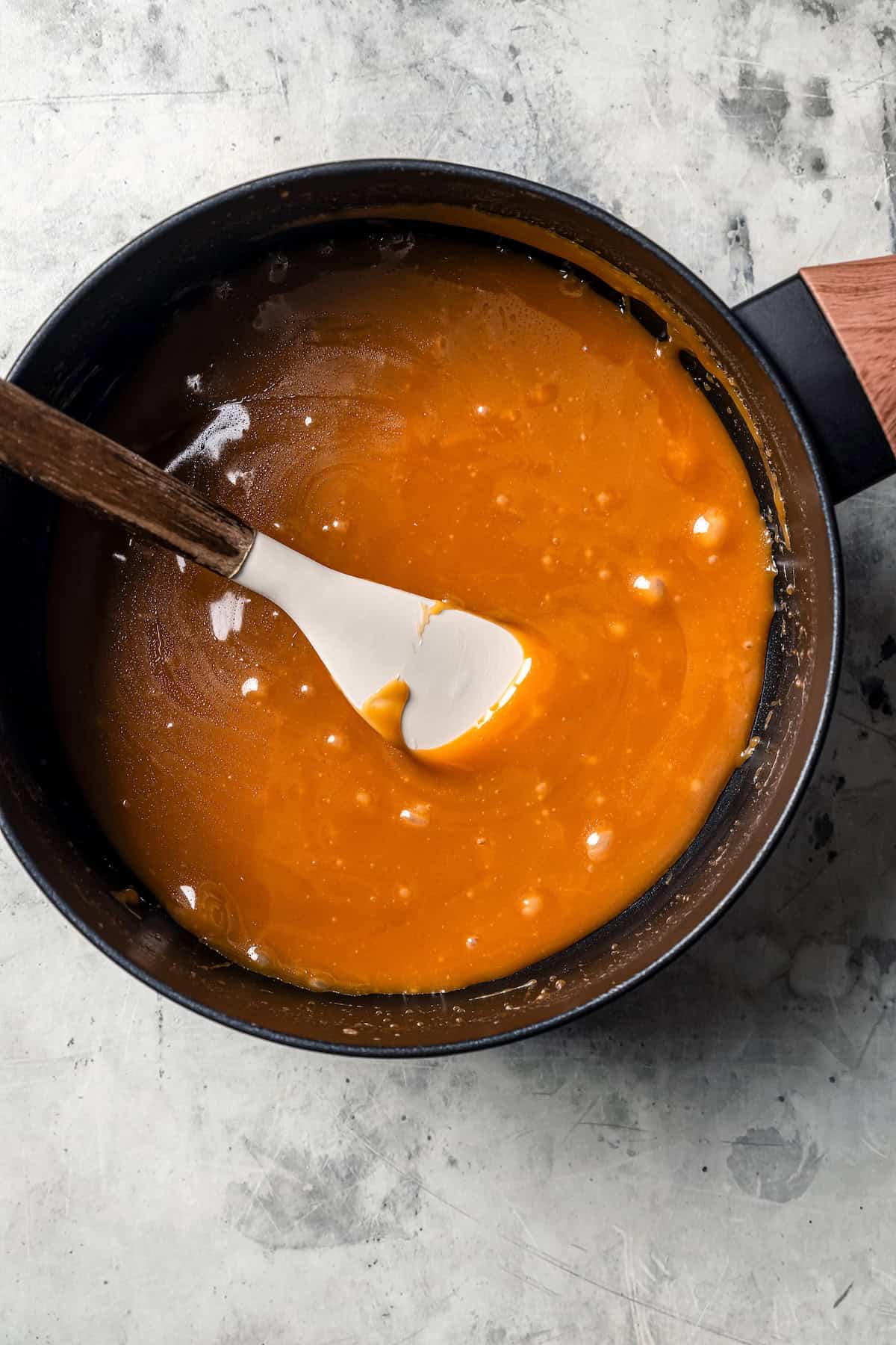 These sweet and gooey homemade caramel rolls require no yeast, rise time, or kneading. They're easy, quick, and best of all, delicious! Caramel filling in a saucepan with a spatula.