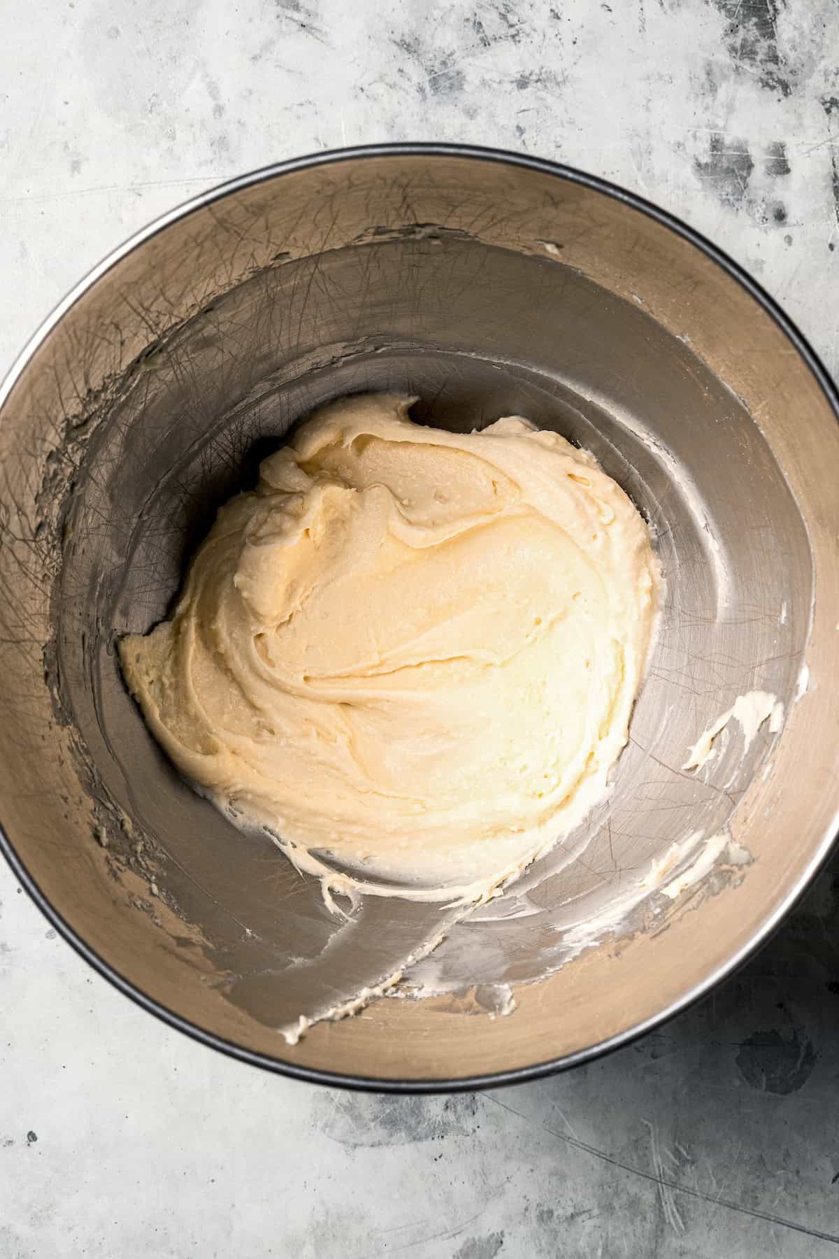 These sweet and gooey homemade caramel rolls require no yeast, rise time, or kneading. They're easy, quick, and best of all, delicious! Frosting in a metal mixing bowl.