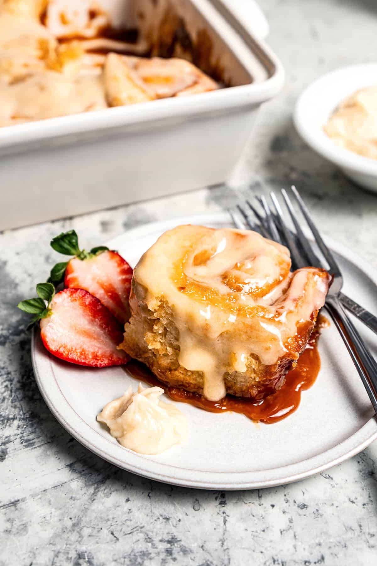 These sweet and gooey homemade caramel rolls require no yeast, rise time, or kneading. They're easy, quick, and best of all, delicious! A caramel roll next to fresh berries on a plate.