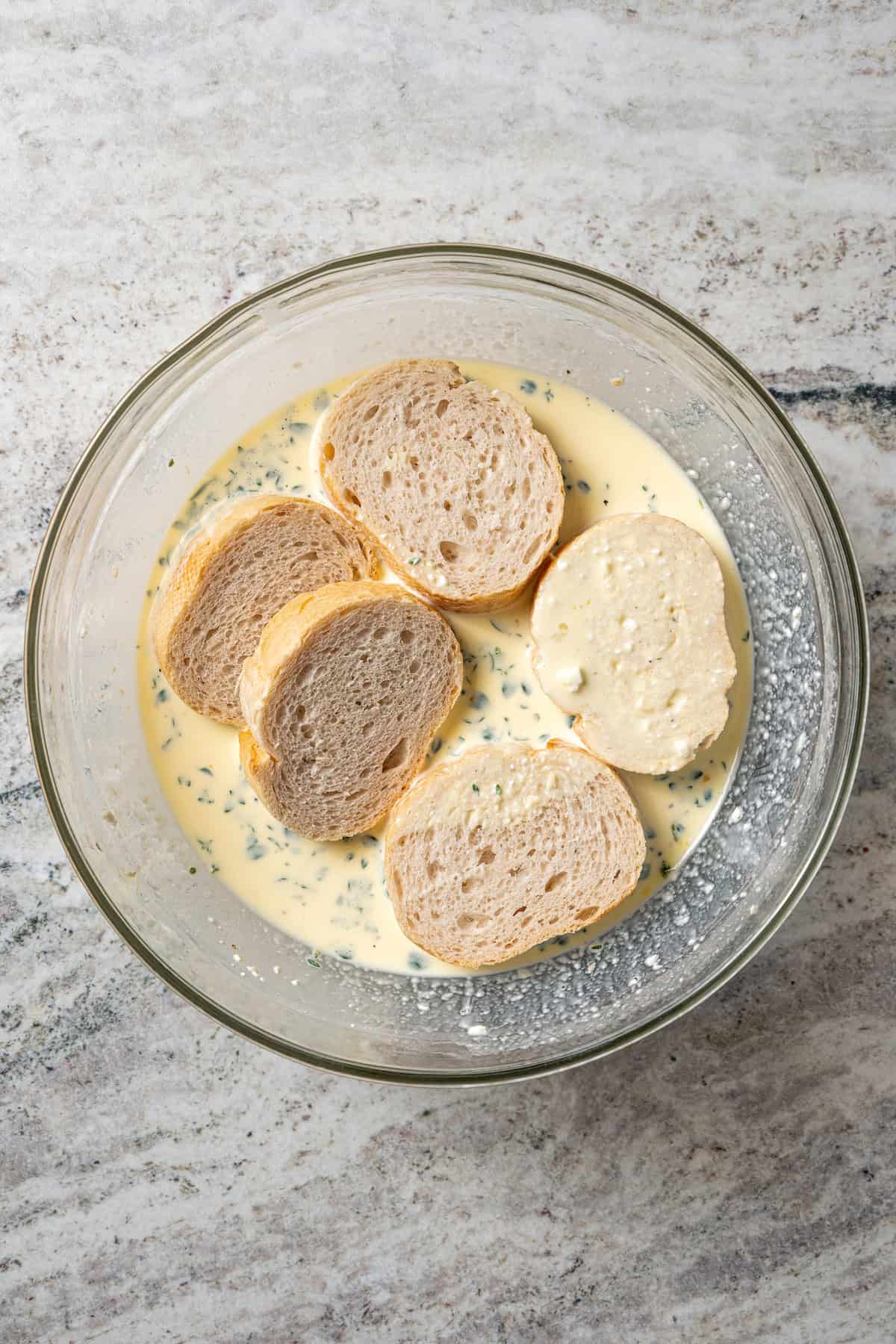 Slices of French bread in a bowl of savory custard.